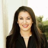 Sara Varnado, founder of A New World Immigration Law, smiling in a black blazer and pearl necklace
