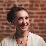 Sarah Pezak, owner of Diamond in the Ruff Pet Spa, smiling in front of a brick wall in a cream blouse