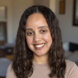 Yadira Fortunato, Dominican American therapist and founder of Think Out Loud Therapy in the Hudson Valley, smiling in a tan sweater with curly dark hair
