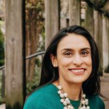 Dr. Zarina Rasheed, board-certified pediatric dentist and owner of Z Pediatric Dentistry, smiling in a green dress and pearl necklace