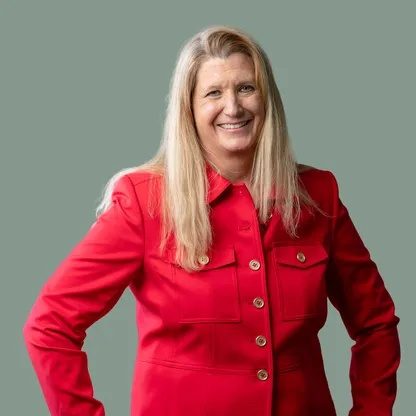 Dr. Tobi Jeurink, founder of Root Function Health, smiling in a red jacket against a sage green backdrop