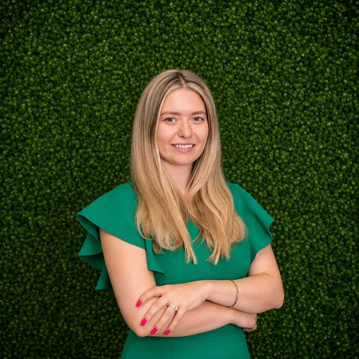 Vera Cap, co-founder of Neo Aesthetics and Medical International Academy, smiling in front of the academy's green wall