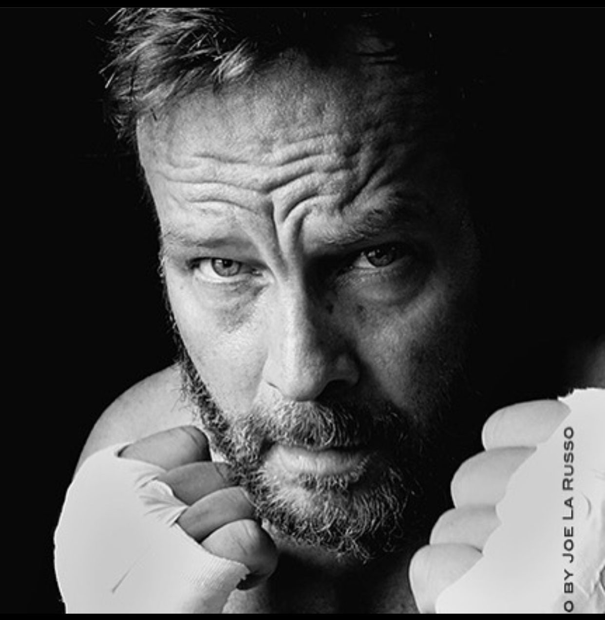 Black and white portrait of William Sanford in boxing hand wraps, fists raised to his chin