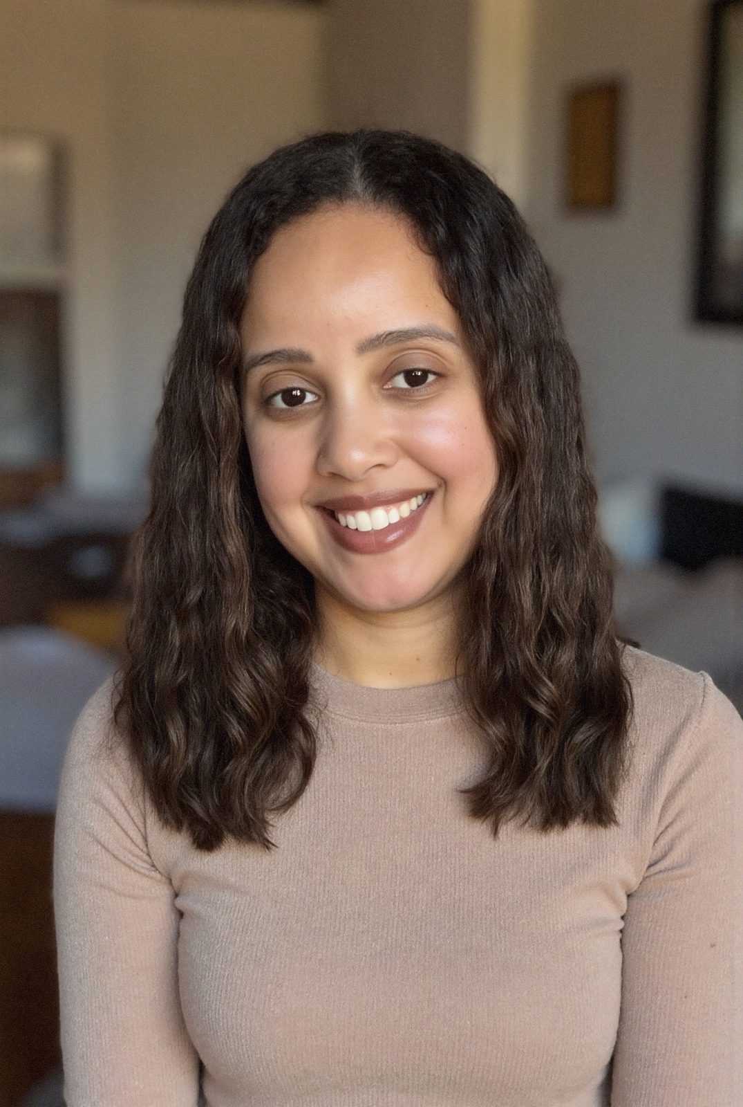 Yadira Fortunato, Dominican American therapist and founder of Think Out Loud Therapy in the Hudson Valley, smiling in a tan sweater with curly dark hair